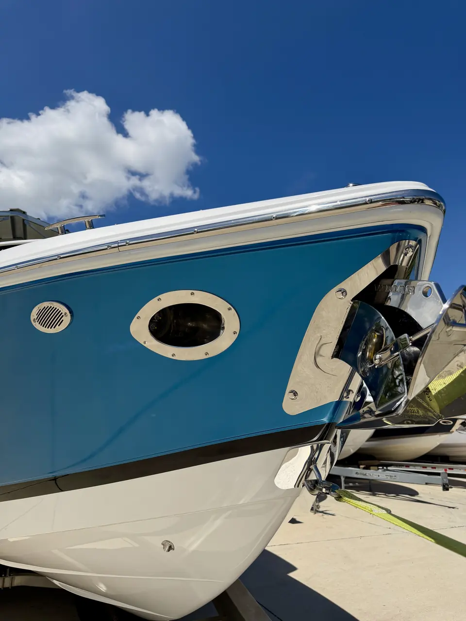 Bow of a boat in a gloss blue hull wrap against a clear sky