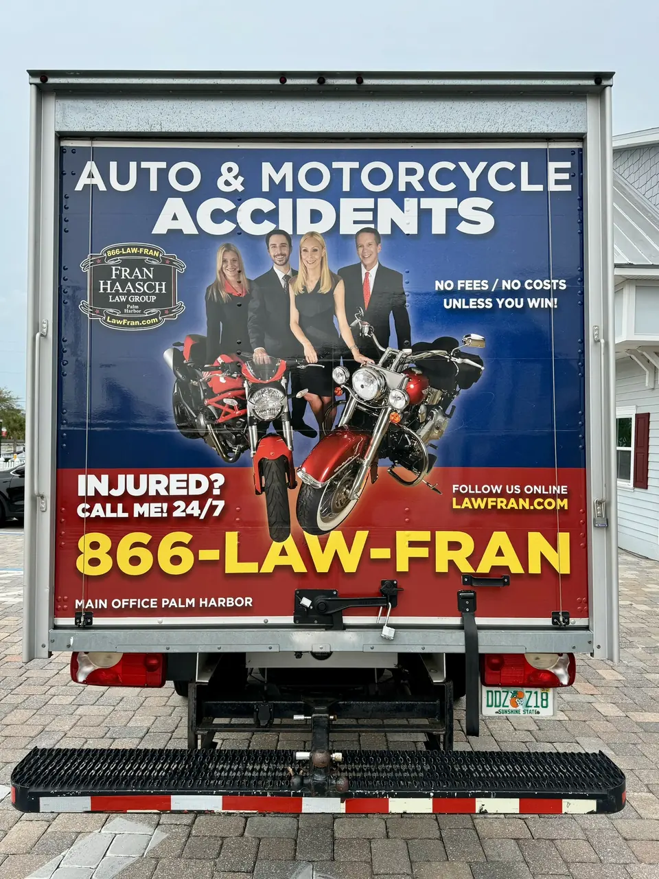 Rear roll-up door of a box truck wrapped with an accident law advert