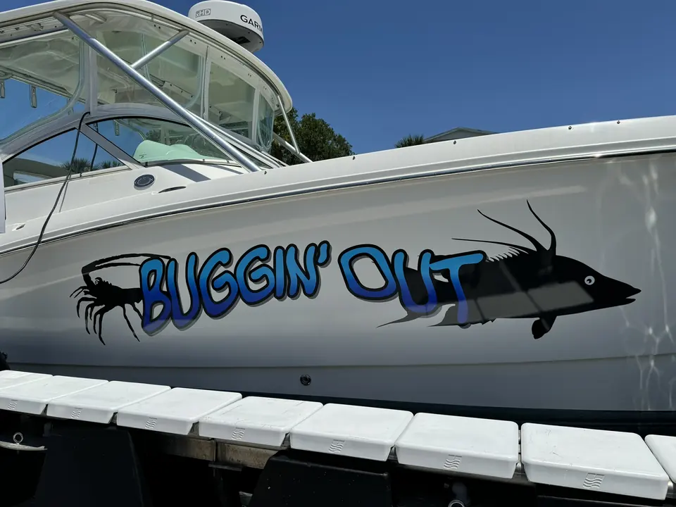 Buggin' Out boat name in blue with a black shrimp graphic on a center console