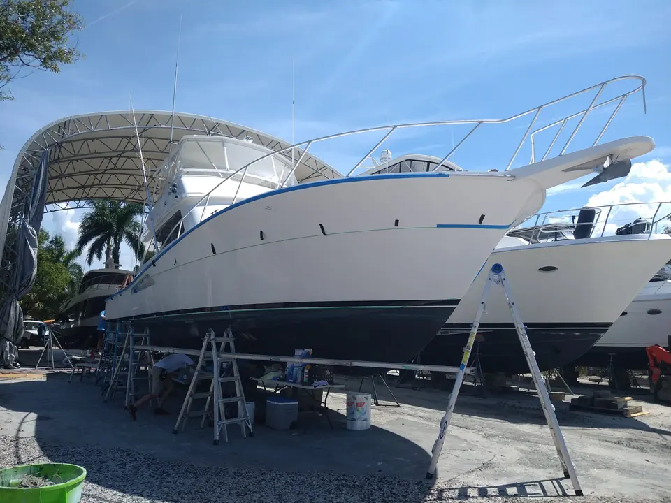 Express cruiser on stands with a navy boot stripe going on under a shade cover