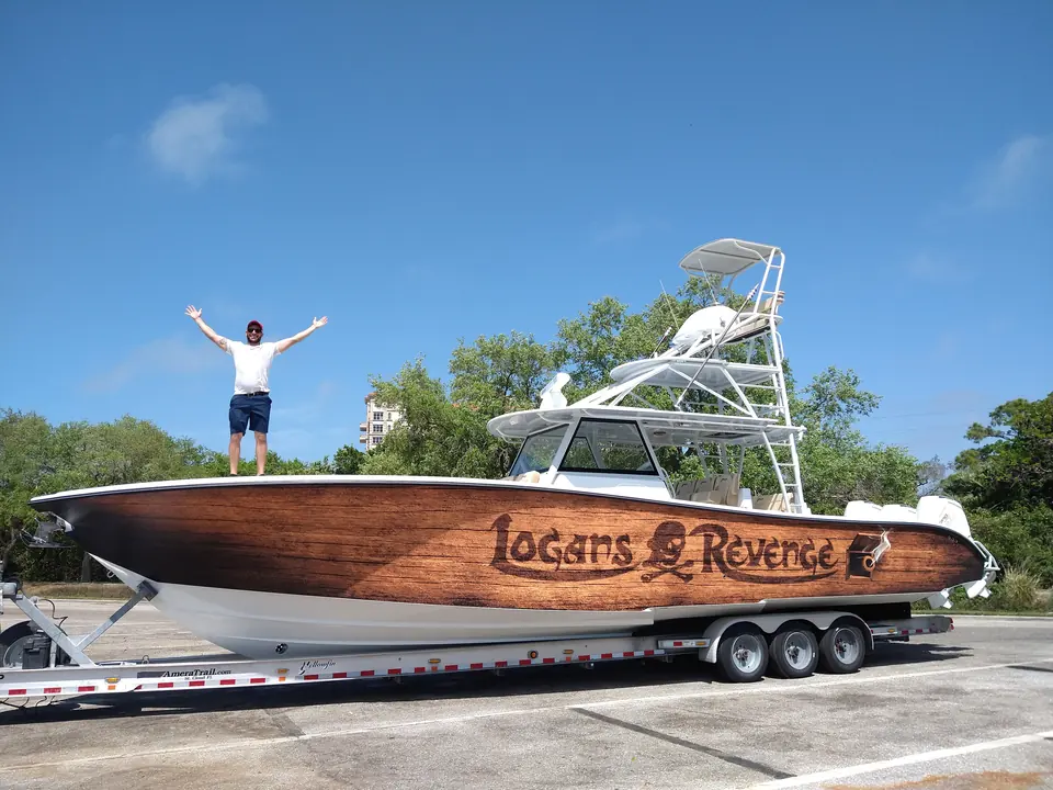 Center console boat in a full faux-teak wrap with the name Logan's Revenge, owner standing on the bow