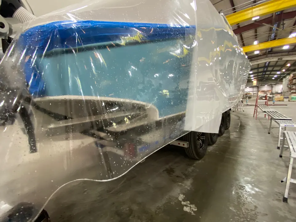 Clear paint protection film being laid over a light-blue hull