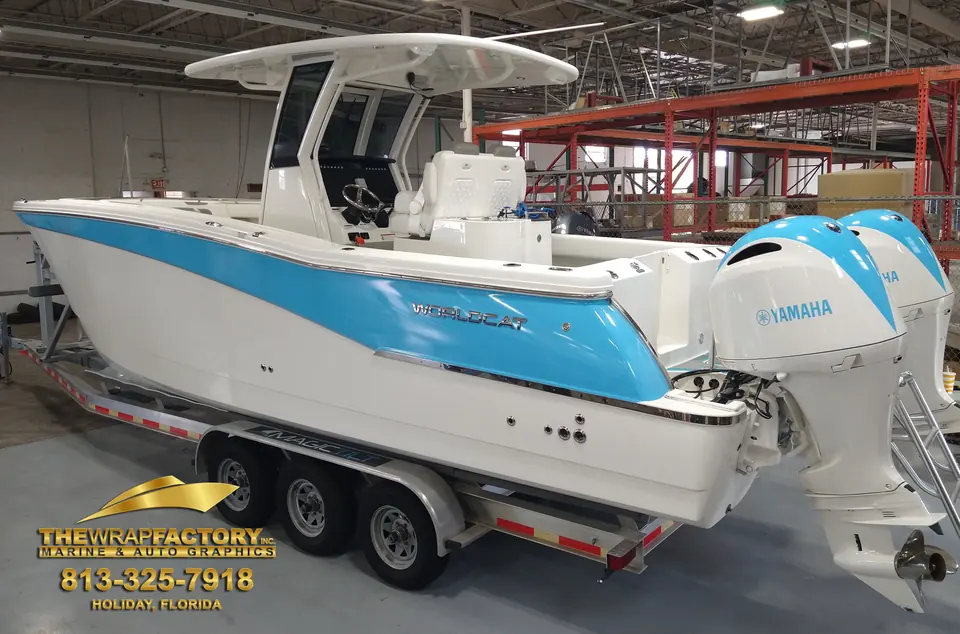 Center console with a sky-blue hull wrap on its trailer in the shop