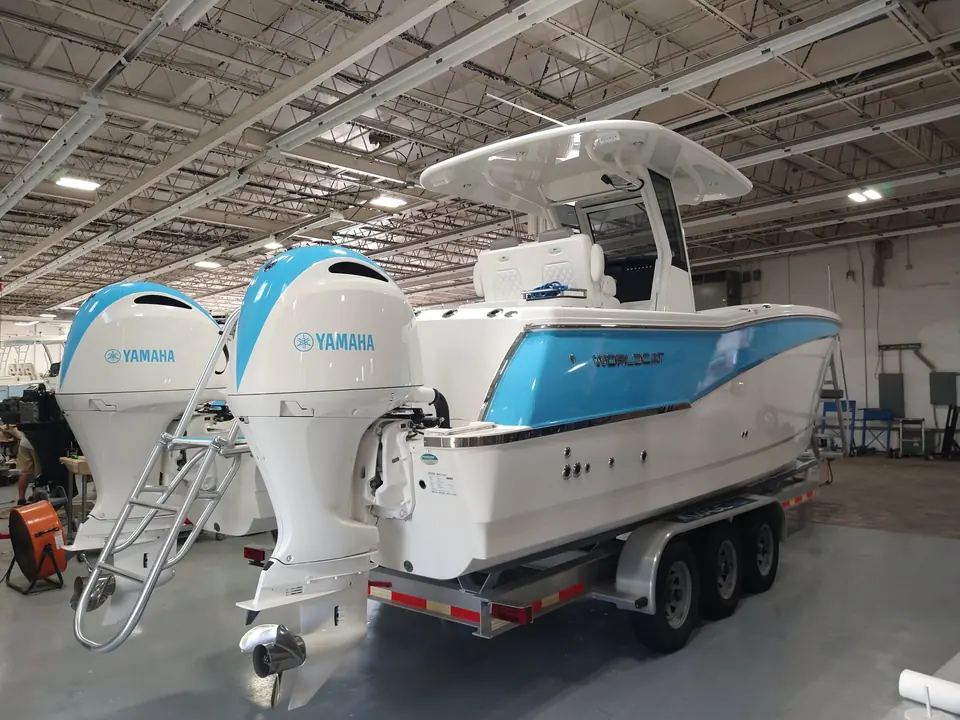 Center console with a light-blue hull wrap and twin Yamaha outboards in the shop