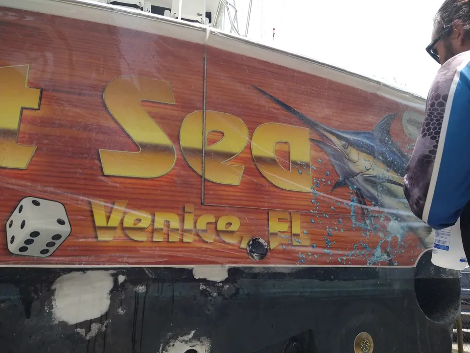 Close-up of the Yacht Sea, Venice FL faux-teak transom wrap with dice artwork
